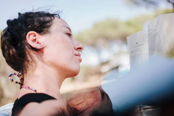 Jovem mulher lendo um livro em um parque em um dia ensolarado — Fotografia de Stock