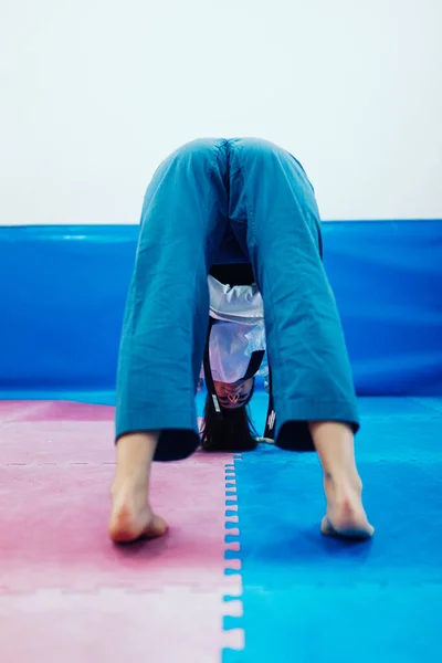 Giovane donna che si estende in un dojo indossa taekwondo dobok — Foto Stock