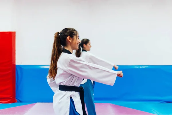Két fiatal nő gyakorolja a taekwondo-t egy edzőteremben. — Stock Fotó