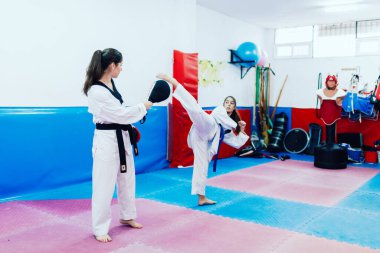 İki genç kadın bir eğitim merkezinde tekvando çalışıyor.