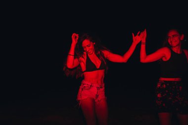 Bir grup genç kadın gece göldeki bir partide kırmızı ışıkta eğleniyorlar.