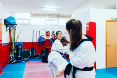 İki genç kadın bir eğitim merkezinde tekvando çalışıyor.