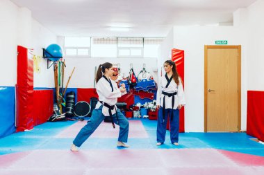 İki genç kadın bir eğitim merkezinde tekvando çalışıyor.