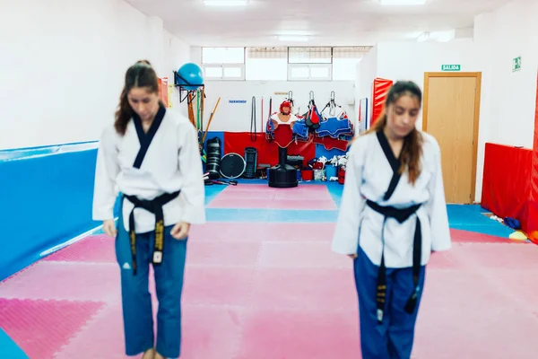 Two unrecognizable out-of-focus women performing the taekwondo salute before the battle — Stock Photo, Image