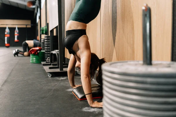 Mujer joven entrenando en el suelo en un gimnasio practicando handstand walk — Foto de Stock