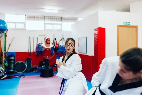 Két fiatal nő gyakorolja a taekwondo-t egy edzőteremben. — Stock Fotó