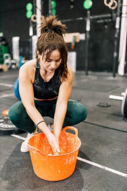 Tanınmayan bir kadın ağırlık kaldırmak için ellerine magnezyum uyguluyor.