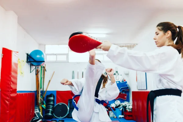 Two young women practice taekwondo in a training center — Stock Photo, Image