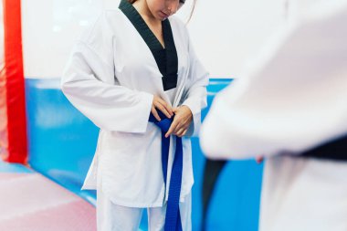 İki genç kadın birbirlerine tekvando kimonolarını giydirirler.