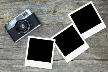 Ahşap yüzey üzerinde boş fotoğraf çerçeveleri ile eski analog kamera