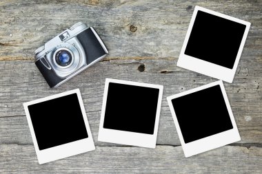 Ahşap yüzey üzerinde boş fotoğraf çerçeveleri ile eski analog kamera