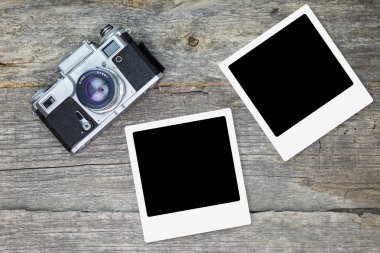 Ahşap yüzey üzerinde boş fotoğraf çerçeveleri ile eski analog kamera