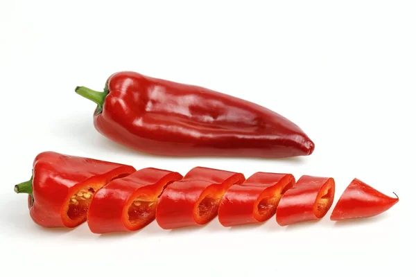 Spetsiga röd paprika och en skuren i bitar, på vit bakgrund. — Stockfoto