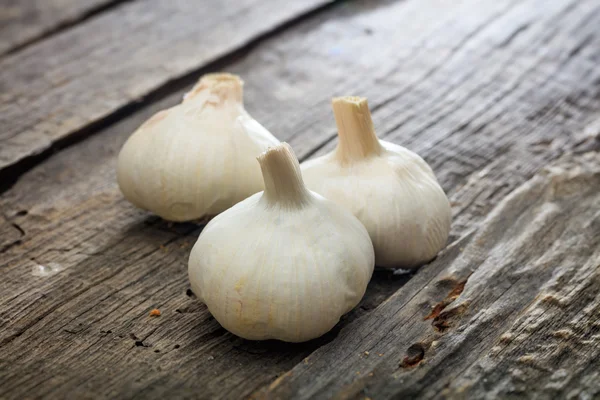 Three garlic bulbs, on wooden surface — Stock Photo, Image