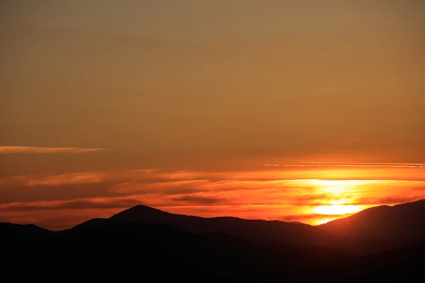 Majestoso pôr do sol vívido / nascer do sol sobre silhuetas de montanhas escuras — Fotografia de Stock