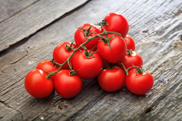 Dois cachos de tomate cereja vermelho, na superfície de madeira — Fotografia de Stock