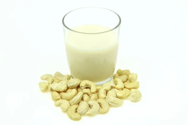 Hoop van rauwe cashewnoten en een glas melk cashew, op witte achtergrond. — Stockfoto