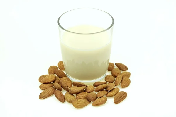 Heap of almonds and a glass of almond milk, on white background. — Stock Photo, Image