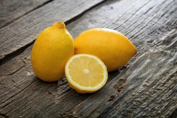 Two lemons and one half, on wooden surface — Stock Photo, Image