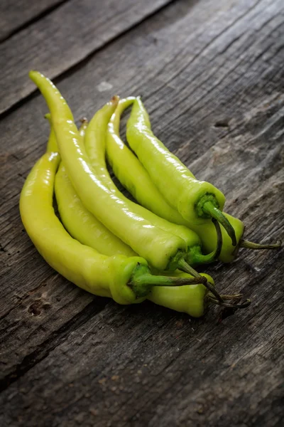 Pila di peperoncini verdi, su superficie di legno — Foto Stock