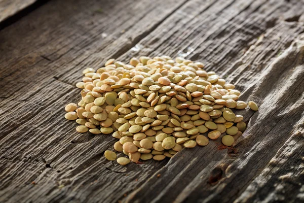 Brown lentils set on old wooden surface — Stock Photo, Image
