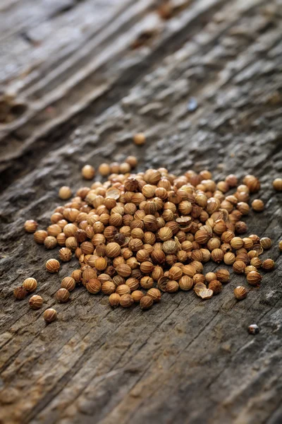 Dried coriander seeds in a pile set on old wooden surface — Stock Photo, Image