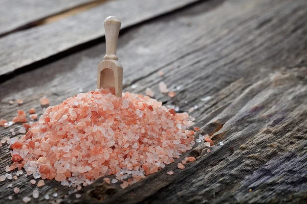 A heap of pink Himalayan salt, on wooden surface. — Stock Photo, Image