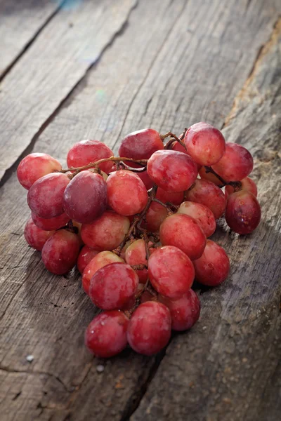 Bando de uvas vermelhas, na superfície de madeira . — Fotografia de Stock