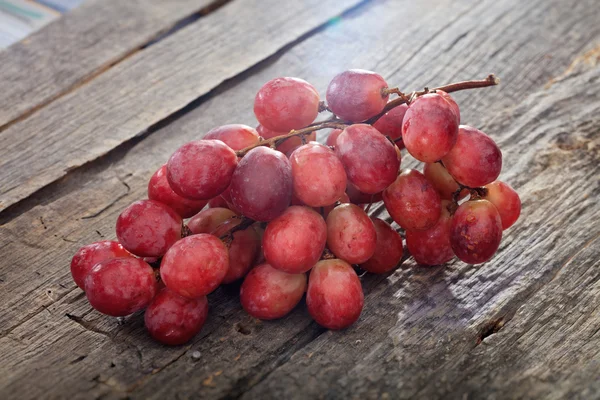 Bando de uvas vermelhas, na superfície de madeira . — Fotografia de Stock