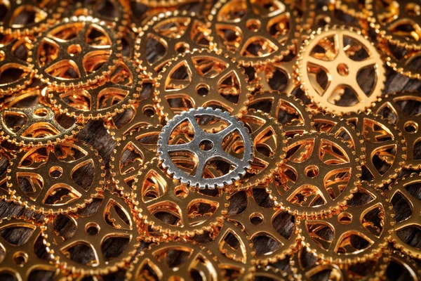 Closeup of bronze cogwheels pile with one silver — Stock Photo, Image