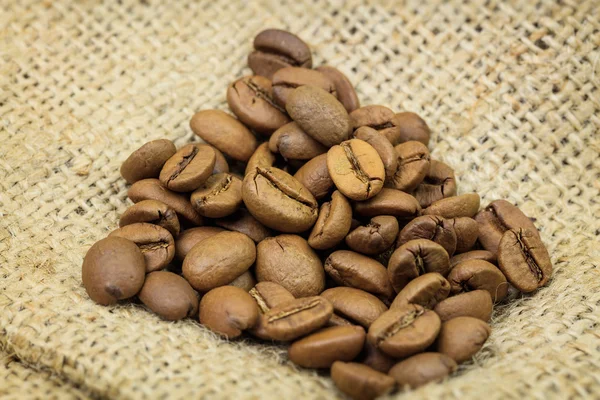 Heap of coffee beans on sackcloth — Stock Photo, Image