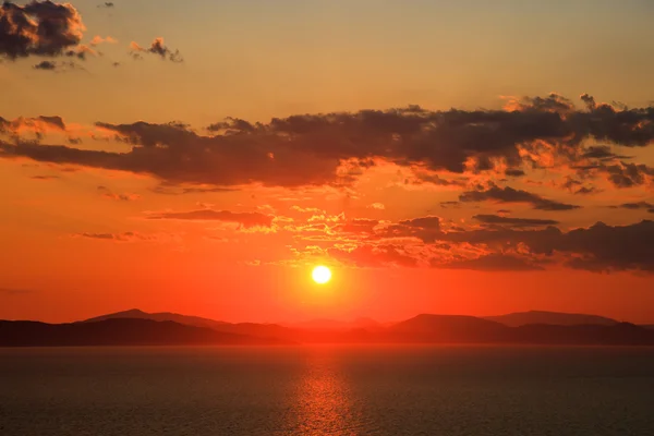 Ηλιοβασίλεμα στο συννεφιασμένο ουρανό πάνω από τα βουνά και τη θάλασσα — Φωτογραφία Αρχείου