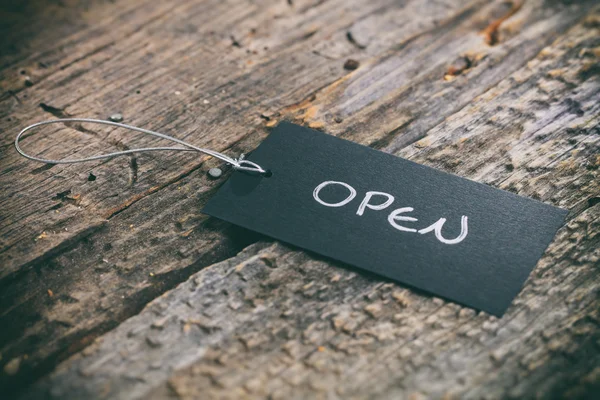 Closeup of pricing tag with twine and "Open" text on wooden background — Stock Photo, Image