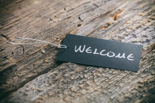 Closeup of pricing tag with twine and "Welcome" text on wooden background — Stock Photo, Image