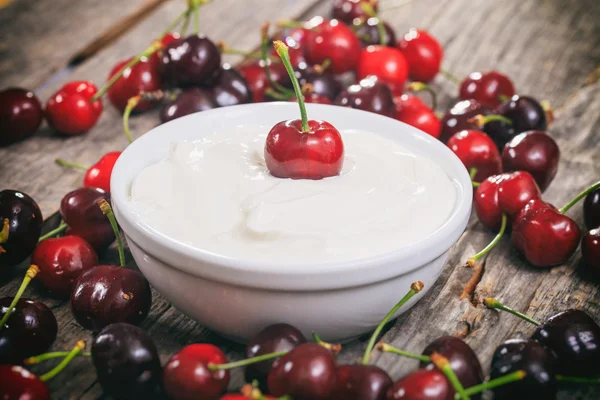 Creamy yogurt with cherries, on wooden surface. — Stock Photo, Image