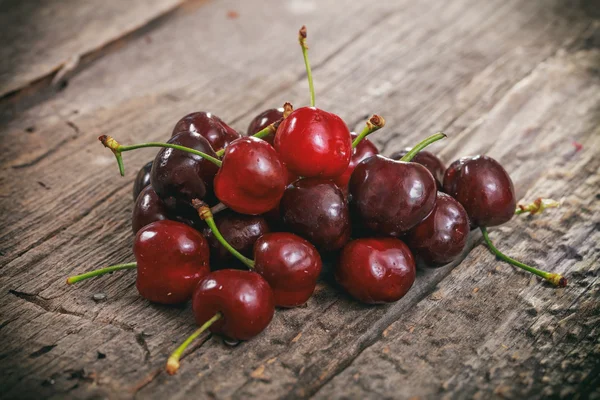 Un montón de cerezas rojas, en la superficie de madera . — Foto de Stock