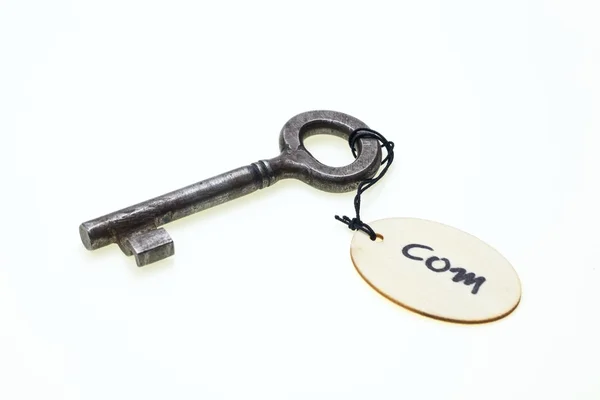 A wooden tag with "com" text on old rusty key, isolated on white background — Stock Photo, Image