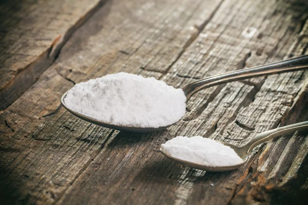 Tablespoon and teaspoon with baking soda, on wooden surface. — Stock Photo, Image