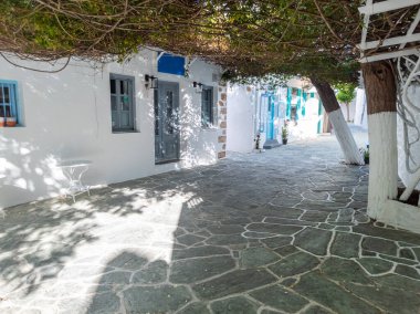 Yunanistan 'ın Folegandros adasındaki asfalt alanı kaplayan bitkilerle sokak manzarası.