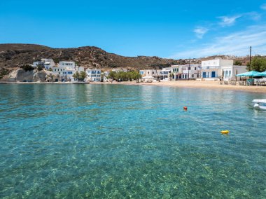 Kimolos adası Psathi limanı Yunanistan. Rocky peyzajı, Cyclades mimarisi, geleneksel badanalı binalar deniz kenarındaki kafeler, şeffaf turkuaz deniz, mavi gökyüzü güneşli yaz günü..
