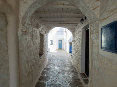 Cyclades 'in varış yeri Yunanistan Kythnos Adası Chora köyü. Beyazlatılmış eski binalar Yunan mimarisi, ahşap kemerli barınak boş, dar kaldırım taşlı bir sokağı kaplıyor. Yaz tatili güneşli bir gün