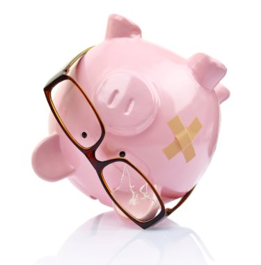 Piggy bank with broken eyeglasses and bandage upside down 