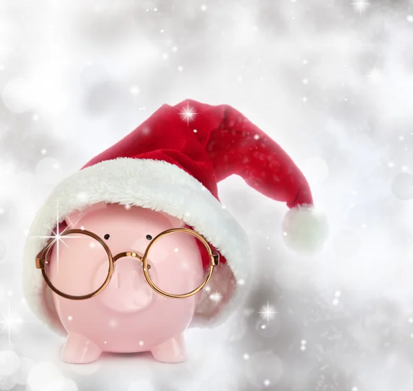 Sparschwein mit Weihnachtsmann-Hut und Brille vor glitzerndem Hintergrund — Stockfoto