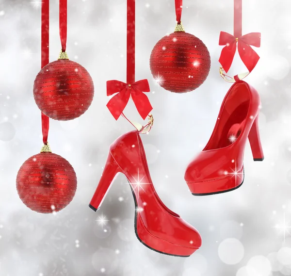 Ψηλά τακούνια παπούτσια και χριστουγεννιάτικα μπάλες κρέμονται από κόκκινη κορδέλα — Φωτογραφία Αρχείου