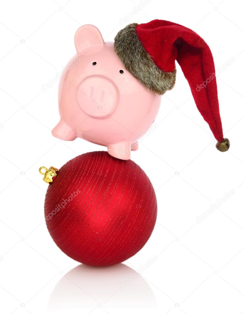 Piggy bank with Santa Claus hat balancing on a Christmas ball