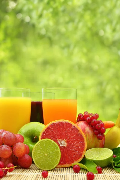 Fresh fruit and three glasses full of juice — Stock Photo, Image