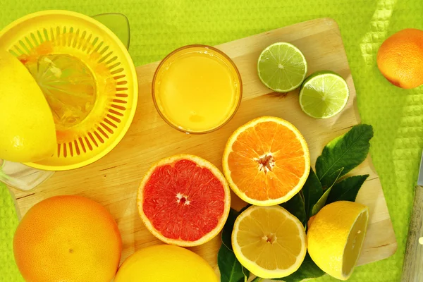 Fatias de citrinos e um suco fresco em uma bandeja de madeira — Fotografia de Stock