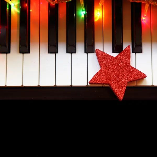 Weihnachtsbeleuchtung und Schmuck auf Klaviertasten — Stockfoto