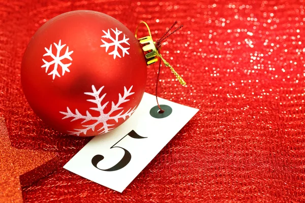 Número cinco na etiqueta e ornamets de Natal no fundo vermelho — Fotografia de Stock