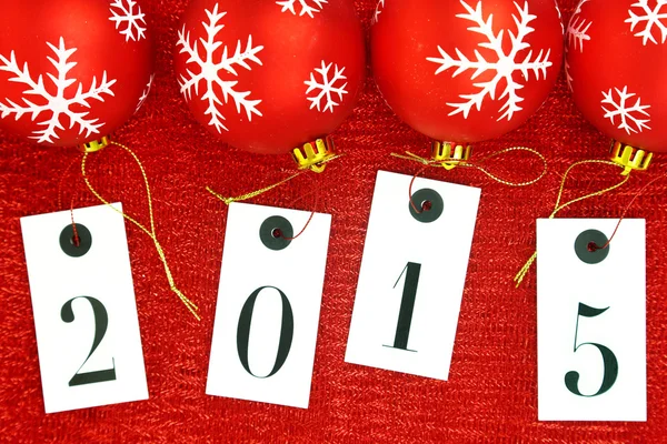 New year 2015 on tags and Christmas balls on red background — Stock Photo, Image